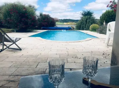 two wine glasses sitting on a table in front of a swimming pool at Studio Peyresol in Villasavary