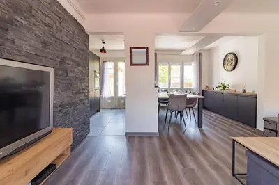 a living room with a large flat screen tv and a stone wall at Ohm Sweet Home - Maison climatisée in Carcassonne