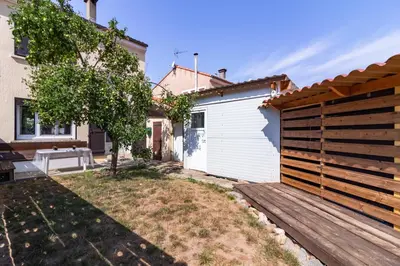 a backyard with a wooden fence and a white garage at Ohm Sweet Home - Maison climatisée in Carcassonne