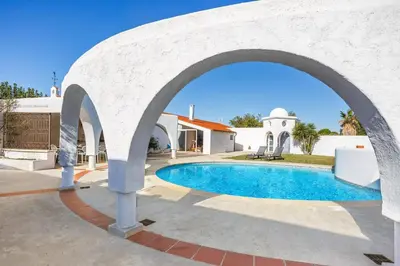 an archway over a swimming pool in front of a house at Villa Les Arches by Villa Plus in Villedaigne