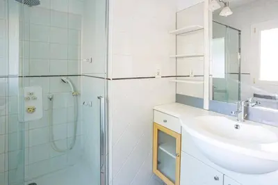 a white bathroom with a sink and a shower at Villa Les Arches by Villa Plus in Villedaigne