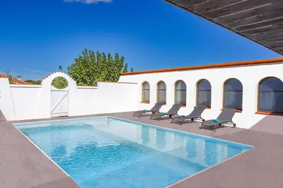 a swimming pool with chairs and a building at Villa Saffron by Villa Plus in Villedaigne