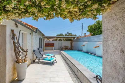 a patio with a pool and a chair next to a house at Villa Le Petit Nid by Villa Plus in Villedaigne