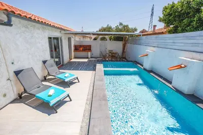 a swimming pool with two chairs next to a house at Villa Le Petit Nid by Villa Plus in Villedaigne