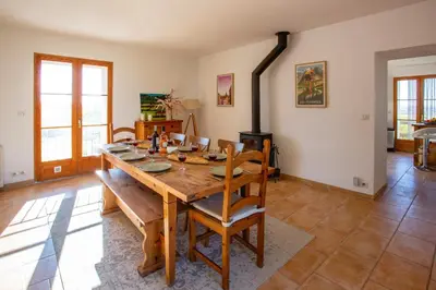 a dining room with a wooden table and a fireplace at Villa Les Juliannes by Villa Plus in Azillanet