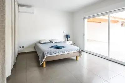 a white bedroom with a bed and a large window at Villa Terre des Vins by Villa Plus in Portel-des-Corbières