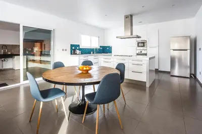 a kitchen with a wooden table and blue chairs at Villa Terre des Vins by Villa Plus in Portel-des-Corbières