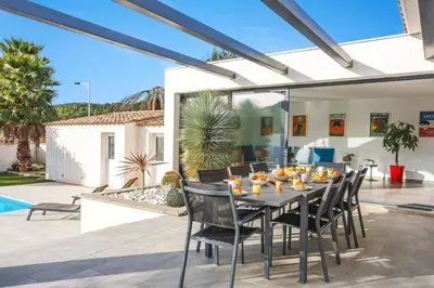 a dining table and chairs on a patio at Villa Terre des Vins by Villa Plus in Portel-des-Corbières
