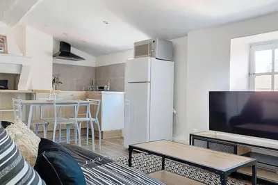 a white bedroom with a large bed and a chair at Le Pradel in Carcassonne