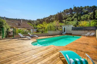 a swimming pool with chairs and a wooden deck at Villa Fraisse by Villa Plus in Fraissé-des-Corbières
