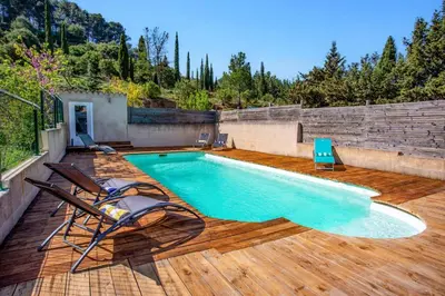 a swimming pool on a wooden deck with two chairs at Villa Fraisse by Villa Plus in Fraissé-des-Corbières