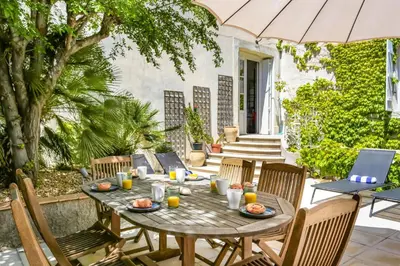 a wooden table with chairs and an umbrella on a patio at Villa La Fontaine by Villa Plus in Capestang