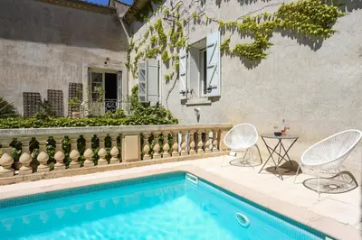 a swimming pool with two chairs and a table next to a house at Villa La Fontaine by Villa Plus in Capestang