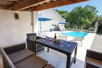 a patio with a table with wine glasses and a pool at Villa Domaine Saint Roch by Villa Plus in Gaja-et-Villedieu