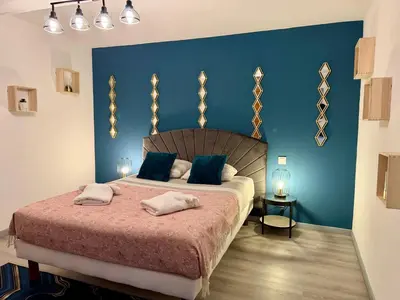a bedroom with a large bed with blue walls at La Bastide in Carcassonne