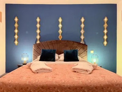 a bedroom with a large bed with blue walls at La Bastide in Carcassonne