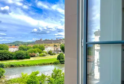 a window with a view of a river and buildings at Chez Pierrot - Pont-Neuf - Vue Cité Médiévale in Carcassonne