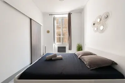 a bedroom with a black bed with a window at Appartement central confortable et spacieux in Carcassonne