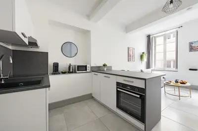 a kitchen with white walls and black appliances at Appartement central confortable et spacieux in Carcassonne