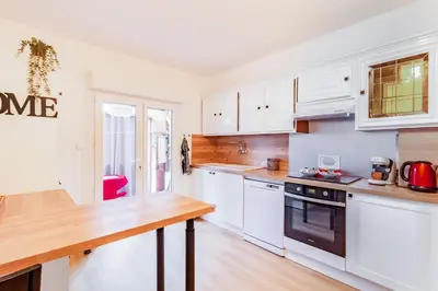 a kitchen with white cabinets and a wooden counter top at La Douce Occitane - Maison climatisée pour 6 in Carcassonne