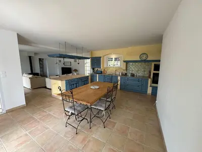 a kitchen with blue cabinets and a wooden table and chairs at Villa Les amandiers avec piscine in Saint-Laurent-de-la-Cabrerisse