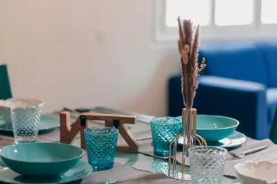 a table with plates and bowls and a vase with grass at Villa Terra Mera piscine privée proche de Narbonne in Cuxac-dʼAude