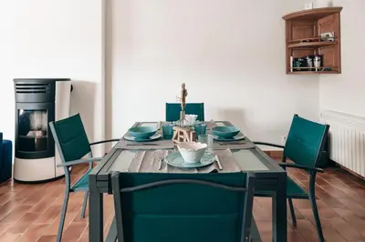 a dining room table with green chairs and a refrigerator at Villa Terra Mera piscine privée proche de Narbonne in Cuxac-dʼAude
