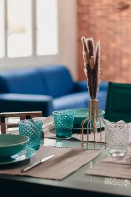 a table with plates and a vase with feathers at Villa Terra Mera piscine privée proche de Narbonne in Cuxac-dʼAude