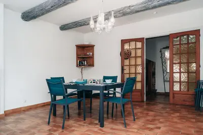 a dining room with a black table and blue chairs at Villa Terra Mera piscine privée proche de Narbonne in Cuxac-dʼAude