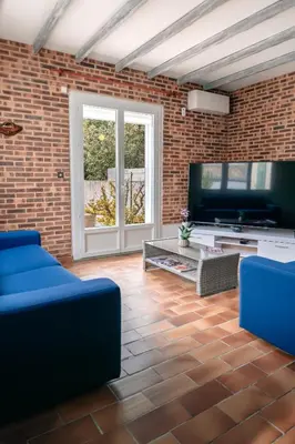 a living room with a blue couch and a tv at Villa Terra Mera piscine privée proche de Narbonne in Cuxac-dʼAude