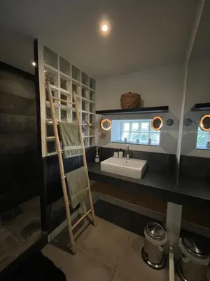 a bathroom with a sink and a wooden chair at La Tuilerie du Bazalac in Trèbes