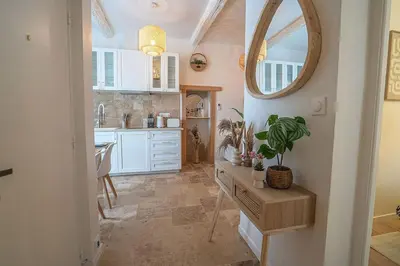 a kitchen with white cabinets and a table with a potted plant at Évasion scandinave à Narbonne élégance et confort réunis ! in Narbonne
