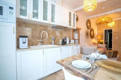 a kitchen with white cabinets and a counter top at Évasion scandinave à Narbonne élégance et confort réunis ! in Narbonne