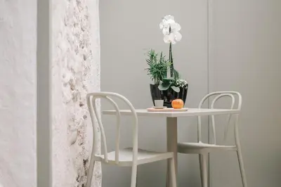 a table with two chairs and a vase with white flowers at La Demeure de la Cité by Jean Bacou in Carcassonne