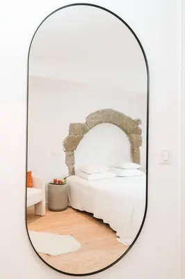 a mirror in a white room with a bed at La Demeure de la Cité by Jean Bacou in Carcassonne