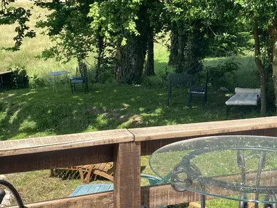 a wooden railing with a glass table in a yard at Maison NATURALY in Laprade