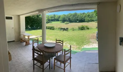 a patio with a table and chairs and a view of a field at Maison NATURALY in Laprade