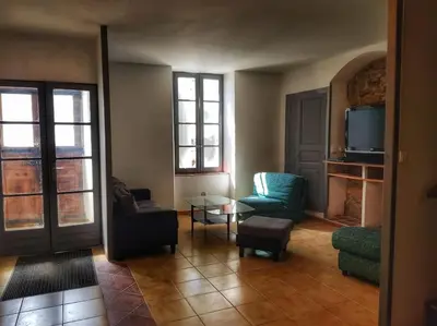a living room with a couch and chairs and a tv at La maison des Chevaliers in Campagne-sur-Aude