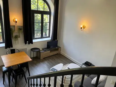 a room with a table and a desk with a television at Le Bourgeois Grand T2 in Carcassone