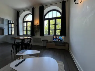 a living room with two tables and two windows at Le Bourgeois Grand T2 in Carcassone
