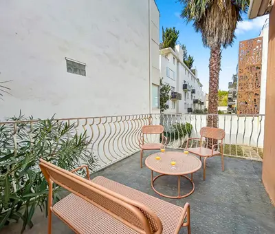 a patio with benches and a table and a palm tree at La Maison Rose - Proche Centre Ville in Narbonne