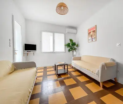 a living room with two couches and a table at La Maison Rose - Proche Centre Ville in Narbonne