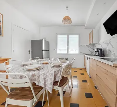 a dining room with a table and chairs in a kitchen at La Maison Rose - Proche Centre Ville in Narbonne