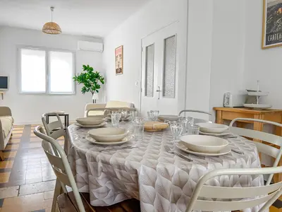 a dining room with a table with plates and chairs at La Maison Rose - Proche Centre Ville in Narbonne