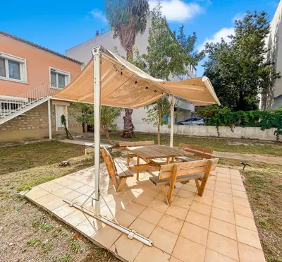 a picnic table with a canopy in a yard at La Maison Rose - Proche Centre Ville in Narbonne
