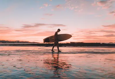 a man walking on the beach with a surfboard at mobile home 047 in Port-la-Nouvelle