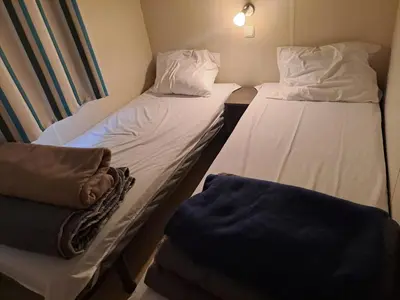 two beds in a small room with white sheets at mobile home 047 in Port-la-Nouvelle