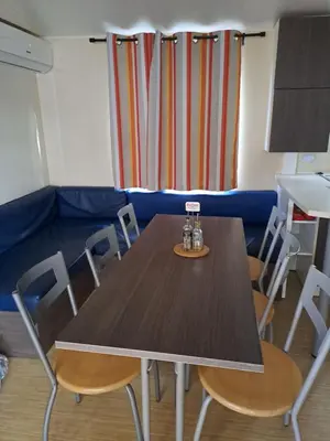 a table in a room with chairs and a couch at mobile home 047 in Port-la-Nouvelle