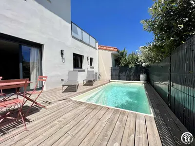 a swimming pool on a wooden deck with a table and chairs at Gite sainte louise in Narbonne