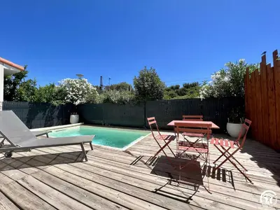 a deck with a table and chairs next to a pool at Gite sainte louise in Narbonne